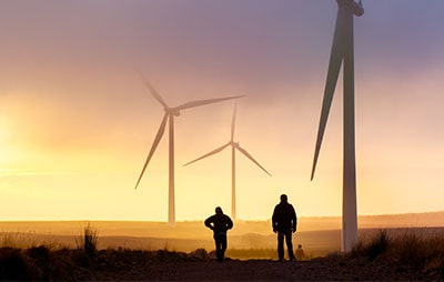 People looking at wind turbines at sunrise
