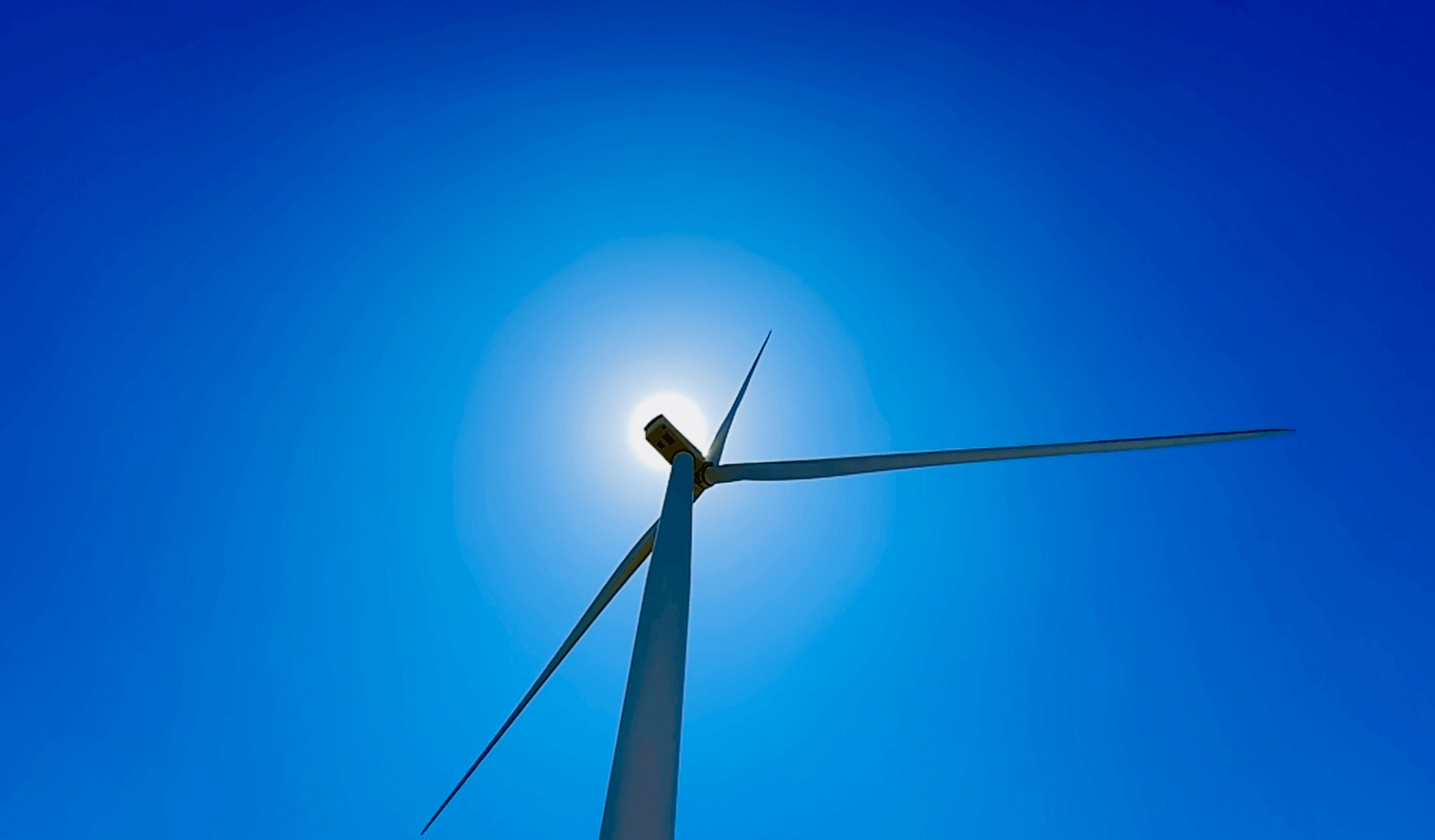 Wind turbine against the sky with sun in background